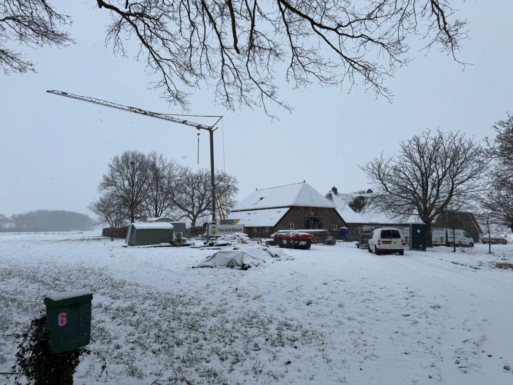 Bouwplaats met kraan bij de monumentale stal in Zuidloo in de sneeuw